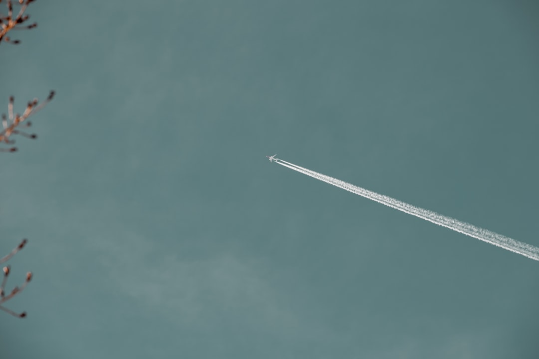 Airplane flying high against a blue teal sky